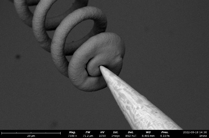 The top of a 3D printed copper microscale spring, being contacted by a robotic prober.